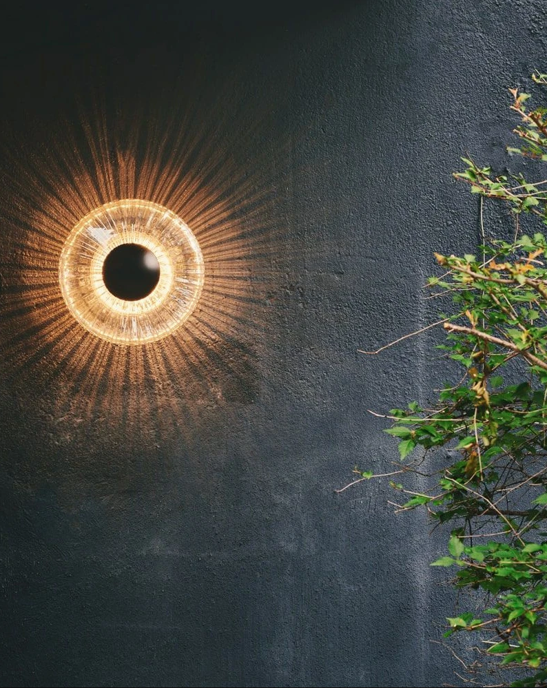 New Wave Optic Udend&oslash;rs v&aelig;glampe  med rund glassk&aelig;rm der ligner et &oslash;je med sort pupil i midten. Lyset spredes ud med linjer